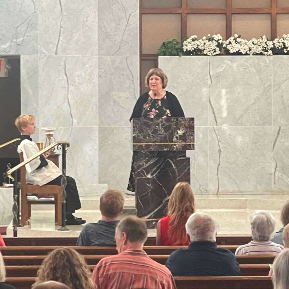 Diann Bomkamp speaking at a podium about the Rural Parish Clinic